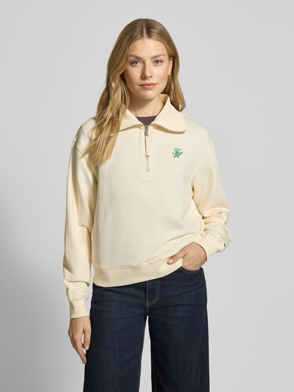 Vrouwenmodel draagt Regular Fit Sweatshirt uit katoenmix van Tommy Hilfiger, crème, unicolor, groene logo-stitching, lange mouw, ribboorden, troyerkraag, zweetstof, vooraanzicht van het hele lichaam.