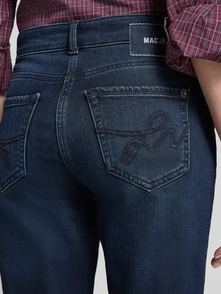Frauenmodel trägt Regular Fit Straight Fit Jeans winterwarm angeraut von MAC Jeans, dunkelblaue Denim-Textur, 5-Pocket-Design, sichtbare Nähte, Ganzkörperansicht Rückansicht.