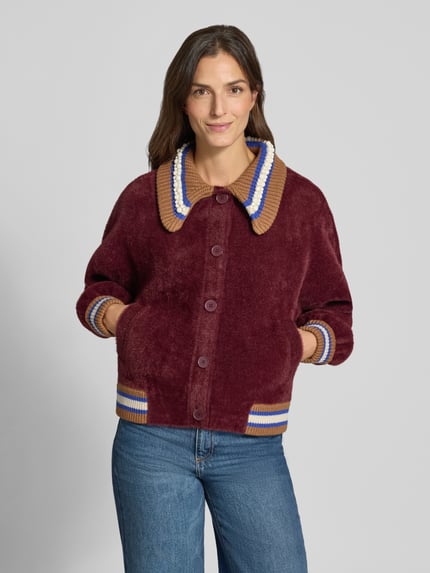 Frauenmodel trägt Strickjacke mit Kontrastkragen Modell 'KAMORE' von Essentiel Antwerp, mehrfarbig mit Label-Schriftzug und Kontraststreifen, gerippte Bündchen, einreihige Knopfleiste, Umlegekragen, Langarm, Nahaufnahme Oberkörper.