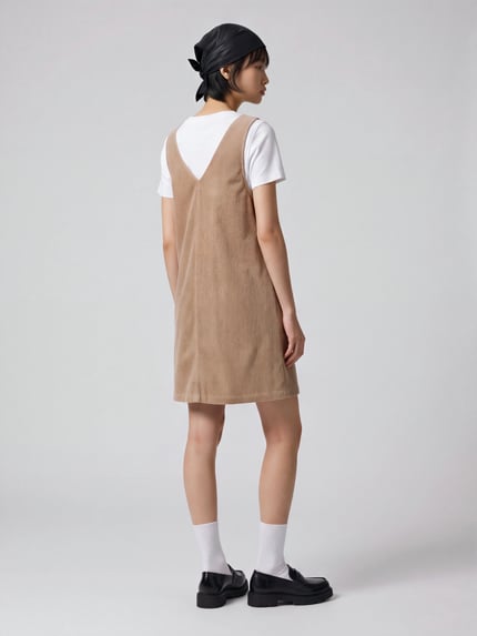 Frauenmodel trägt Minikleid aus Cord mit aufgesetzten Taschen von MOP DENIM in Beige, unifarben, gerade geschnittener Saum, Ganzkörperansicht Rückansicht.