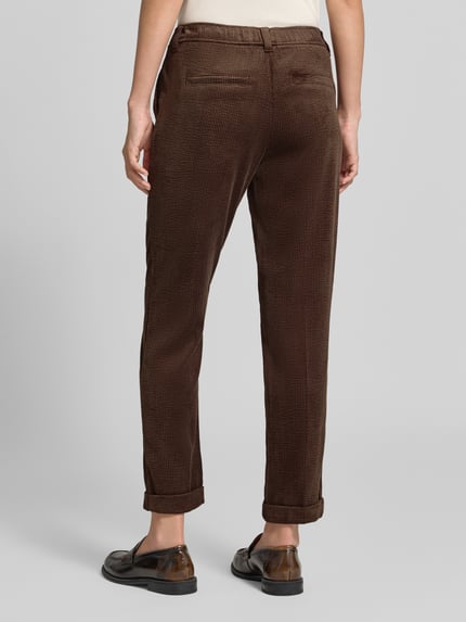 Frauenmodel trägt Cordhose mit elastischem Bund von Christian Berg Woman in Dunkelbraun, Tapered Fit, sichtbare Cordstruktur, Ganzkörperansicht Rückansicht. Material-Mix mit Stretch-Anteil, seitliche Eingrifftaschen, angedeutete Gesäßleistentaschen, Bundweite 38 cm, Innenbeinlänge 70 cm.