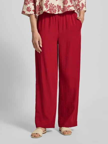 Frauenmodel trägt Stoffhose aus Viskose-Mix mit Tunnelzug Modell 'Daria' von MSCH Copenhagen, Relaxed-Fit, kräftiges Rot, Ganzkörperansicht von vorne. Damen Stoffhose mit Leinen-Viskose-Anteil, elastischer Bund, Bundweite Größe S 39 cm, Innenbeinlänge 78 cm.