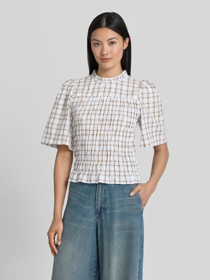 Modelka kobieca ma na sobie Slim Fit Bluse im Allover-Look Modell 'POSSINI' od Neo Noir, biały bawełniany miks w kratę, krój slim fit, stójka, długość tyłu 50 cm, długość rękawa 34 cm, widok całej sylwetki z przodu.