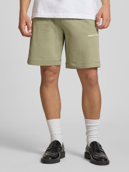 Männermodel trägt Shorts mit Label-Stitching Modell 'KARL' von Jack & Jones, Baumwoll-Mix, Relaxed-Fit, seitliche Eingrifftaschen, Ganzkörperansicht von vorne.