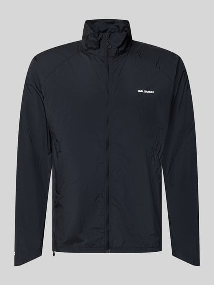 Produktfoto, czarna Jacke mit Stehkragen und Logo von Salomon, krój regular fit, logo, zamek, długość tyłu w rozmiarze M: 70 cm, szerokość ramion w rozmiarze M: 42 cm, szerokość klatki piersiowej w rozmiarze M: 61 cm, długość rękawa w rozmiarze M: 66 cm