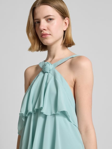 Frauenmodel trägt Volant Abendkleid mit V-Ausschnitt Modell 'FELICIA' von Vero Moda, unifarbenes Maxi-Chiffonkleid, Nahaufnahme Oberkörper.