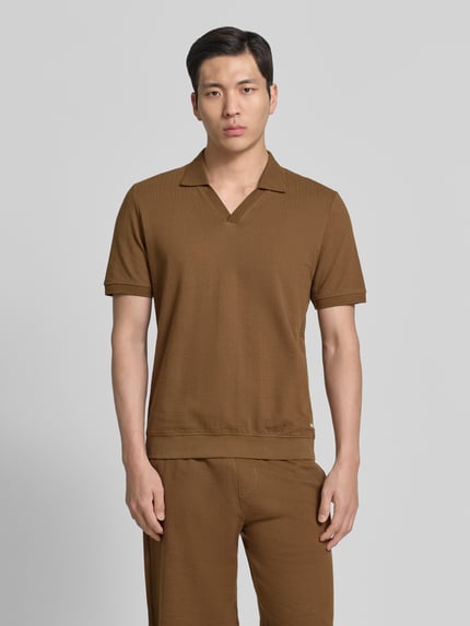 Männermodel trägt Regular Fit Poloshirt aus reiner Baumwolle van s.Oliver RED LABEL in effen bruin jersey met label patch, v-hals, korte mouwen, gestructureerd oppervlak, voorkant volledige lichaamsweergave.