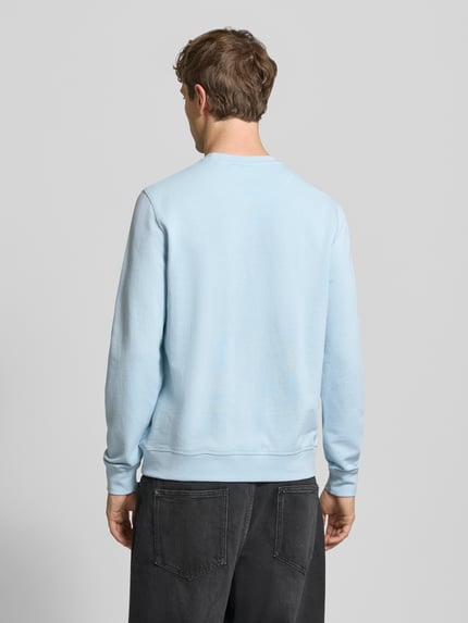 Männermodel trägt Regular Fit Sweatshirt mit floraler Applikation Modell 'Felica' von Blend, reine Baumwolle, elastische Abschlüsse, Ganzkörperansicht Rückansicht.