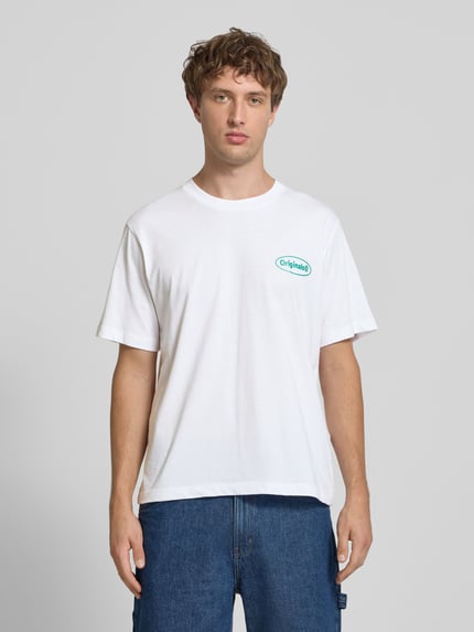 Männermodel trägt T-Shirt mit Logo-Print Modell 'RIVIERA VINTAGE POSTER' von JACK & JONES in Weiß, reine Baumwolle, Straight Fit, Ganzkörperansicht von vorne.