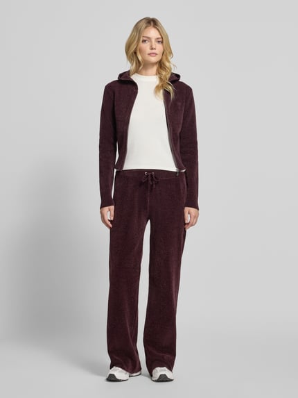 Frauenmodel trägt bordeauxrote Sweathose mit Tunnelzug von Juicy Couture, unifarben, Kordeln, elastischer Bund, Ganzkörperansicht von vorne.