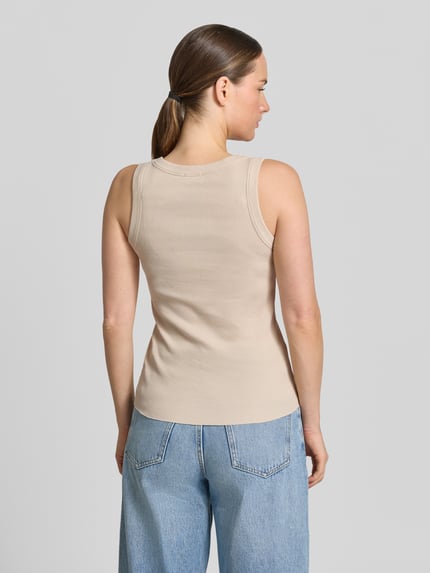 Modelka kobieca ma na sobie beżowy Tanktop mit Rundhalsausschnitt Modell 'TAVIRA' od Drykorn z czystej bawełny, dopasowany krój, prążkowana faktura, długość tyłu w rozmiarze S: 41 cm, widok całej sylwetki z tyłu.
