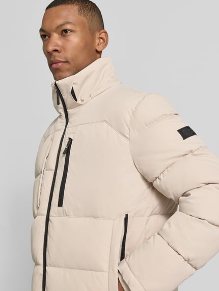 Männermodel trägt Regular Fit Steppjacke mit Brusttasche von s.Oliver RED LABEL in unifarbener Struktur mit Reißverschlusstaschen, Nahaufnahme Oberkörper.
