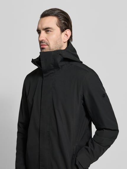 Männermodel trägt Parka mit Ärmelriegeln Modell 'GEORGE' von Didriksons in Schwarz, glatte Textur, Regular Fit, Nahaufnahme Oberkörper. Rückenlänge 94 cm, Schulterbreite 45 cm, Brustweite 55 cm, Ärmellänge 67 cm.