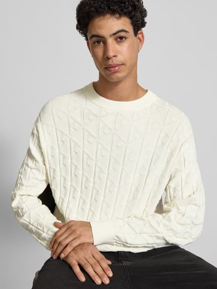 Männermodel trägt Strickpullover mit Rundhalsausschnitt Modell 'EASY' von Calvin Klein Jeans in Weiß, strukturierte Oberfläche, Nahaufnahme Oberkörper, reine Baumwolle, Regular Fit.