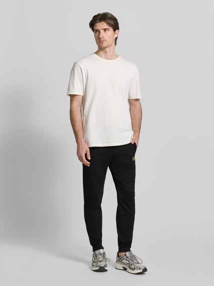 Männermodel trägt schwarze Sweatpants mit Logo und elastischem Bund von EA7 Emporio Armani, Baumwoll-Elasthan-Mix, Regular Fit, Ganzkörperansicht von vorne.