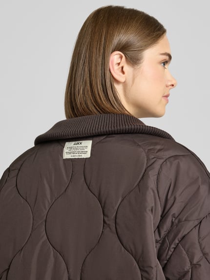 Frauenmodel trägt Steppjacke mit gestricktem Stehkragen Modell 'SERENA' von JJXX in Dunkelbraun, Steppnähte, Detailaufnahme Rückansicht.