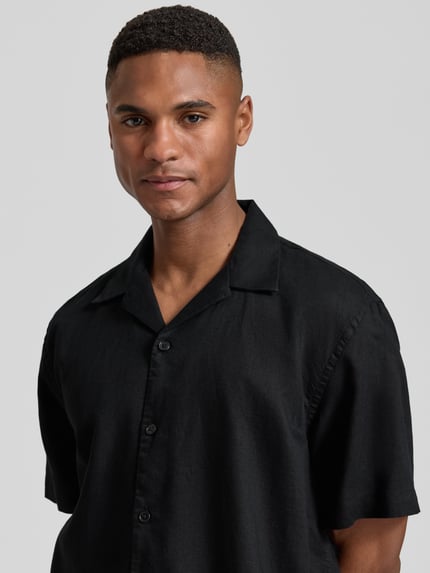 Męski model nosi Relaxed Fit Freizeithemd aus Leinen-Baumwoll-Mix Modell 'RLXCLAY' od HUGO, czarny, struktura flammgarn, widok z przodu, zbliżenie na górę.