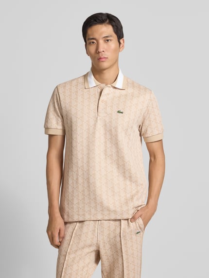 Mężczyzna model nosi Regular Fit Koszulka polo z bawełną od Lacoste, efekt: wzór na całej powierzchni, detal z logo, krój regular fit, wzór w monogramy, wyhaftowane logo, paski w kontrastowym kolorze, kołnierzyk polo, zapięcie na 2 guziki, krótki rękaw, prążkowane zakończenie, wykończenie z rozcięciami po bokach, żakard, całkowity przód.