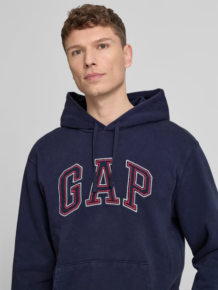 Männermodel trägt Hoodie mit Logo und Känguru-Tasche von GAP in Dunkelblau, Baumwolle-Mix, Regular-Fit, Nahaufnahme Oberkörper.