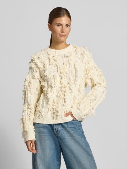 Vrouwenmodel draagt Strickpullover mit Rundhalsausschnitt Modell 'Jennasee' van MSCH Copenhagen, ecrukleur, katoenmengsel met stretch, regular fit, gestructureerd textuur met franjes, combinatie met blauwe jeans, bovenlichaam close-up van voren.