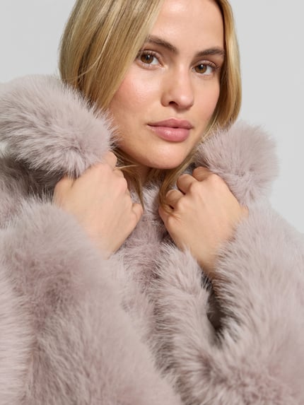 Frauenmodel trägt Flared Jacke aus Kunstfell von ROTATE in Hellgrau mit flauschiger Textur, Innenfutter Viskose-Anteil, Nahaufnahme Oberkörper.
