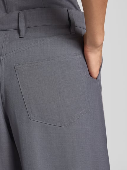 Frauenmodel trägt Wide Fit Stoffhose mit Bundfalten Modell 'Harper' von Samsøe Samsøe, grauer Stoff, glatte Textur, Detailaufnahme Gesäß, Damen Stoffhose, elastischer Material-Mix, KI-modifiziertes Bild.