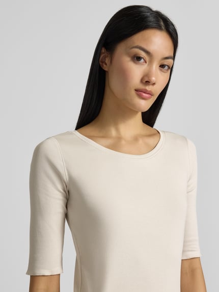 Frauenmodel trägt T-Shirt in Ripp-Optik mit Rundhalsausschnitt von Marc Cain, Slim Fit, cremefarben, Nahaufnahme Oberkörper.