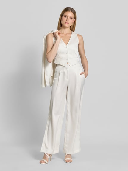 Frauenmodel trägt Hose mit weitem Bein und Falten von Jake*s Cocktail in Creme, aus Satin mit Gesäßtasche, Ganzkörperansicht von vorne.