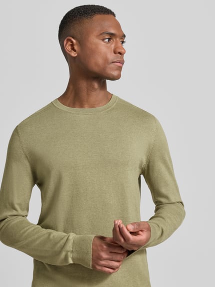 Mannelijk model draagt Regular Fit Pullover aus reiner Baumwolle Modell 'BERG' van SELECTED HOMME, olijfgroen, fijngebreid katoen, uniseks basic, ronde hals, lange mouw, geribde boorden, Nahaufnahme bovenlichaam, voorkant.
