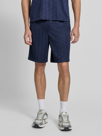 Männermodel trägt Regular Fit Sweatshorts mit Tunnelzug von Lacoste in Dunkelblau mit dezentem Muster, Nahaufnahme Unterkörper, Herren Sweatshorts von Lacoste.