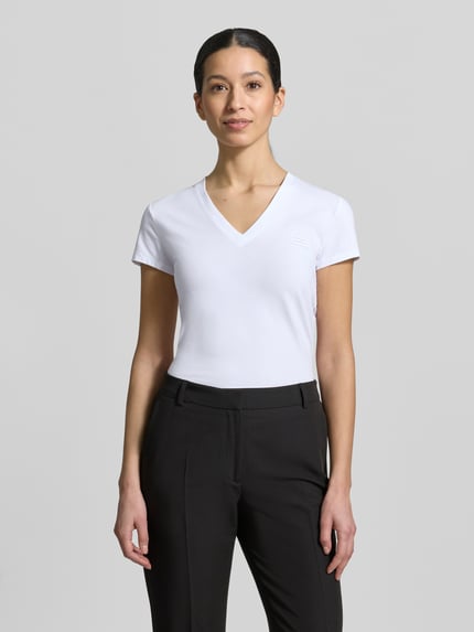Vrouwenmodel draagt T-shirt met V-hals en labelstitching van Armani Exchange, mix van katoen en elastaan, regular fit, ruglengte maat S 63 cm. Ganzkörperansicht von vorne