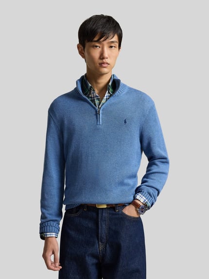 Mannenmodel draagt Regular fit schipperstrui uit puur katoen van Polo Ralph Lauren in lichtblauw, grove textuur, nahaufnahme bovenlichaam.