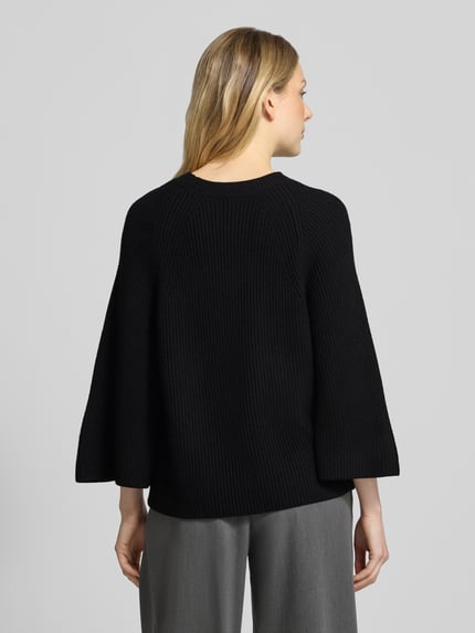 Frauenmodel trägt Pullover aus Wolle mit Trompetenärmeln von BOSS in Schwarz, unifarben, Strukturstrick, Regular Fit, Ganzkörperansicht Rückansicht