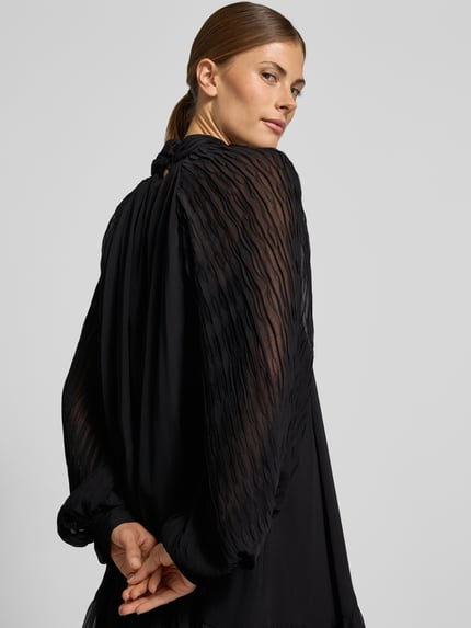 Frauenmodel trägt Minikleid mit Stehkragen Modell 'OLERA' von YAS, A-Linie, fließender schwarzer Stoff, Rückansicht, Nahaufnahme Oberkörper.