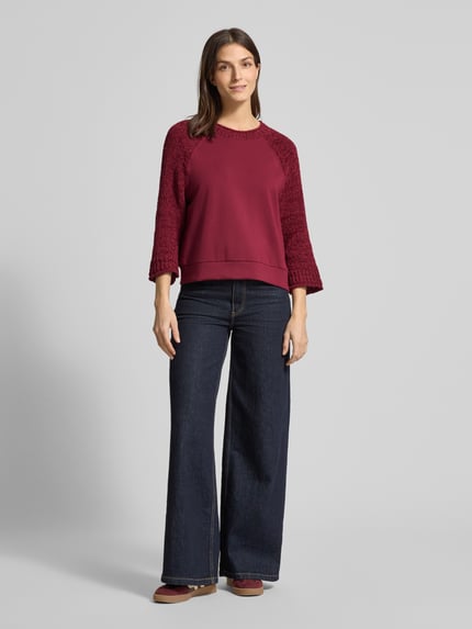 Frauenmodel trägt Relaxed Fit Pullover mit Strick-Besatz von Marc Cain in Dunkelrot, Baumwoll-Mix, Jeans, Ganzkörperansicht von vorne.