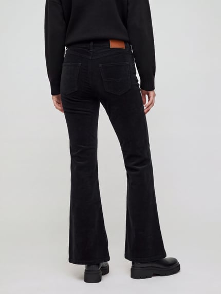 Frauenmodel trägt Cordhose mit ausgestelltem Bein von Pepe Jeans in Schwarz, unifarben, 5-Pocket-Design, Ganzkörperansicht Rückansicht.