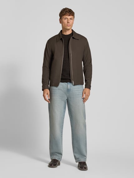 Männermodel trägt Strickpullover aus Viskose-Woll-Mix Modell 'VALDRIK' von DRYKORN, schwarz gemustert, kombiniert mit Jacke und Jeans, Ganzkörperansicht von vorne. Regular Fit, Rundhalsausschnitt, Allover-Look, Rückenlänge und Ärmellänge je 71 cm bei Größe M.