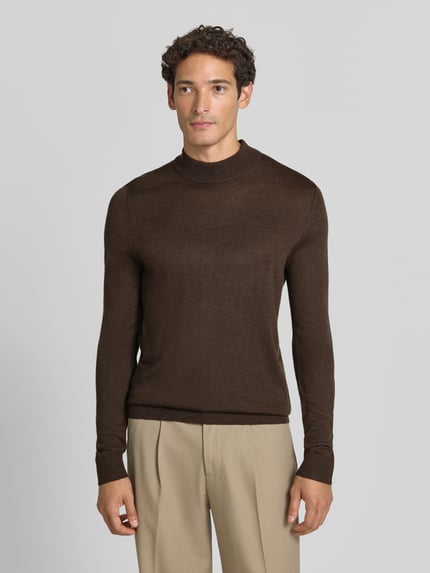 Męski model nosi Regular Fit Turtleneck aus Woll-Mix od Christian Berg Men, brązowa bluzka z długim rękawem, mieszanka wełny, prążkowane wykończenia, prążkowany kołnierz, długość tyłu w rozmiarze M: 69 cm, długość rękawów w rozmiarze M: 51 cm, widok całej sylwetki z przodu.