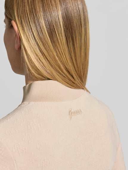 Frauenmodel trägt Slim Fit Sweatjacke mit Stehkragen Modell 'LAUDOMIA' von GUESS, beiges Logo-Muster, Material-Mix mit Stretch, Nahaufnahme Rückansicht.