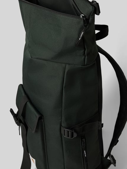 Produktfoto, Rucksack mit Label-Patch Modell 'PHILIS' von Carhartt Work In Progress in dunklem Grün, strukturierte Oberfläche, seitliche Detailaufnahme, Hauptfach mit Überschlag, Klickverschluss, Reißverschluss-Außenfach, verstellbare Schulterriemen, Mesh-Fächer