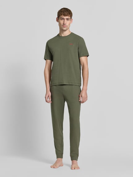 Männermodel trägt Regular Fit T-Shirt aus Baumwoll-Mix von HUGO in Olivgrün, glatte Textur, Ganzkörperansicht von vorne.