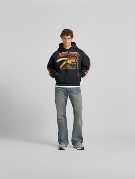 Männermodel trägt Hoodie mit Kapuze von RHUDE aus reiner Baumwolle, Label-Print, Känguru-Tasche, Lockere-Schnitt, Ganzkörperansicht von vorne.