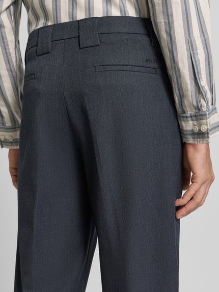 Männermodel trägt Straight Fit Stoffhose aus elastischem Viskose-Mix von MCNEAL in Dunkelblau mit Bügelfalten und Gürtelschlaufen, Nahaufnahme Rückansicht.
