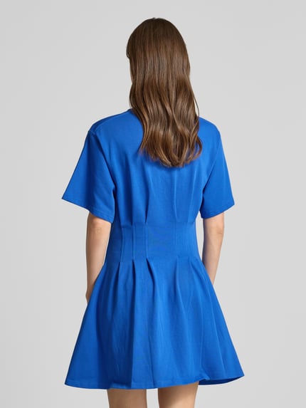 Frauenmodel trägt Leicht ausgestelltes Sweatkleid aus reiner Baumwolle von Polo Ralph Lauren in meliertem Blau mit kurzen Ärmeln, Mini-Länge und gelegten Falten, Ganzkörperansicht Rückansicht.