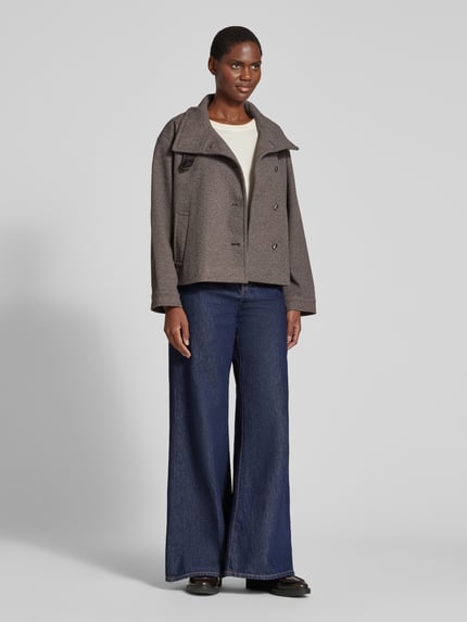 Frauenmodel trägt Bomberjacke mit hohem Stehkragen von VERO MODA in Grau, kombiniert mit weiter Jeans, neutrale Töne, Ganzkörperansicht von vorne.