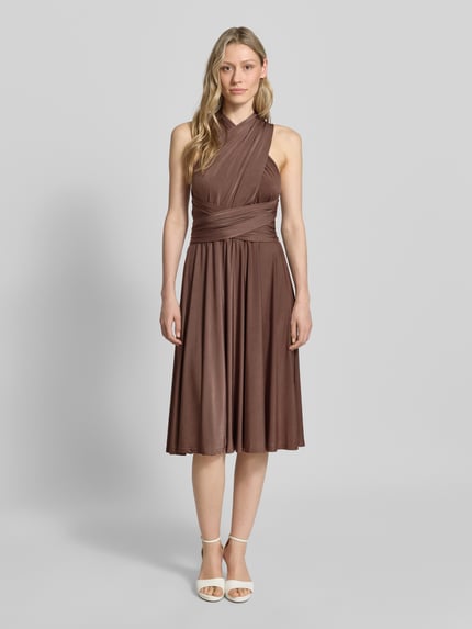 Vrouwenmodel draagt knielange cocktailjurk met diepe V-hals van Rose Avenue, getailleerd model, tailleband, ruglengte maat S 44 cm, Ganzkörperansicht von vorne.