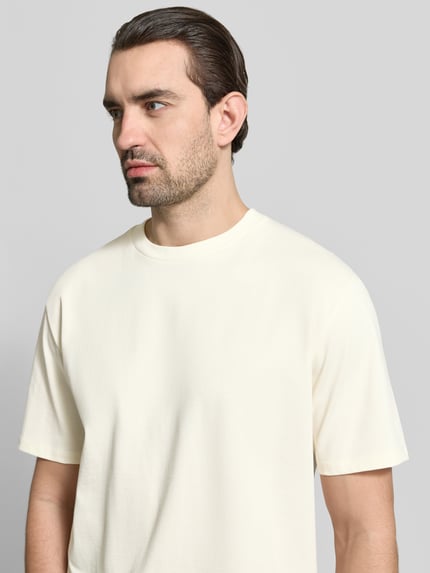 Männermodel trägt Oversized T-Shirt mit Rundhalsausschnitt von Lindbergh in Creme, reine Baumwolle, glatte Struktur, Nahaufnahme Oberkörper.