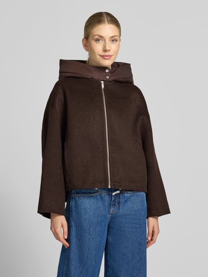 Frauenmodel trägt Oversized Blouson aus Woll-Mix Modell 'Hikone' von OPUS in Dunkelbraun mit breiter Kapuze, Damen Bomberjacke, Nahaufnahme Oberkörper.