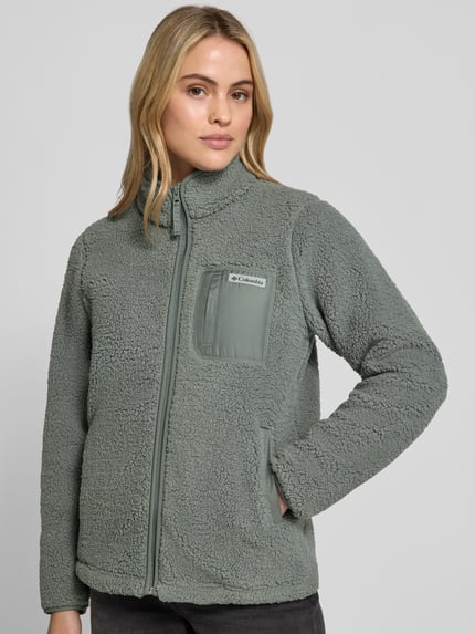 Frauenmodel trägt Fleecejacke mit Stehkragen und Label-Detail von Columbia in Hellgrau, strukturierte Oberfläche, Ganzkörperansicht von vorne. Damen Fleecejacke von Columbia, Regular Fit, Stehkragen, Label-Detail, Reißverschluss, Eingrifftaschen, Rückenlänge bei Größe S: 65 cm, Schulterbreite bei Größe S: 41 cm, Brustweite bei Größe S: 50 cm, Ärmellänge bei Größe S: 64 cm.