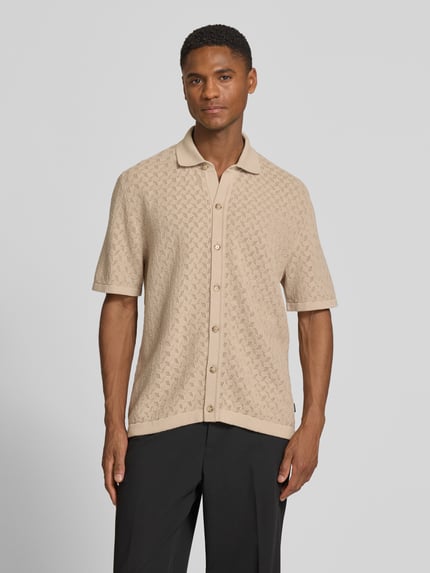 Mężczyznamodel nosi Relaxed Fit Freizeithemd aus reiner Baumwolle Modell NAPPO von BOSS w kolorze beżowym, imitacja dzianiny, krótki rękaw, kołnierzyk polo, listwa guzikowa na całej długości, aplikacja z metką, bawełna, Ganzkörperansicht von vorne.